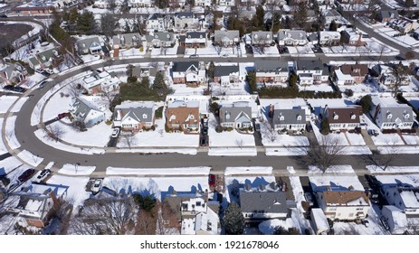 Aerial Drone Camera Shot Over A Suburb Of Long Island, NY In The Morning, After A Snowfall. The Houses Are Arranged Neatly Around A Curved Road.