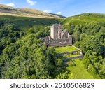 Aerial drone Castle Campbell in Dollar in the Scottish highlands, medieval fort, fortress with fortification and ruin in high mountains and forest in Scotland near Edinburgh with flag blowing in wind