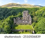 Aerial drone Castle Campbell in Dollar in the Scottish highlands, medieval fort, fortress with fortification and ruin in high mountains and forest in Scotland near Edinburgh with flag blowing in wind