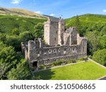 Aerial drone Castle Campbell in Dollar in the Scottish highlands, medieval fort, fortress with fortification and ruin in high mountains and forest in Scotland near Edinburgh with flag blowing in wind