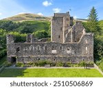 Aerial drone Castle Campbell in Dollar in the Scottish highlands, medieval fort, fortress with fortification and ruin in high mountains and forest in Scotland near Edinburgh with flag blowing in wind