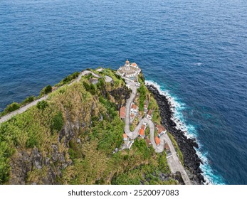 Aerial drone coastal view of Farol do Arnel lighthouse and fishermen's huts. Cliffs, rocky coast, curvy serpentine road and the Atlantic Ocean. Sao Miguel Island, Azores, Portugal - Powered by Shutterstock