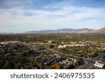 Aerial drone extreme wide landscape shot of the Salt Lake county valley covered in buildings, busy roads, and colorful autumn trees on a warm sunny fall evening in Utah