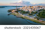 Aerial Drone Fly Above Beautiful Cityscape of Porto Alegre Brazil Neighborhood Gasometro, Guaiba Lake, Architecture and Road Traffic with Warm Skyline