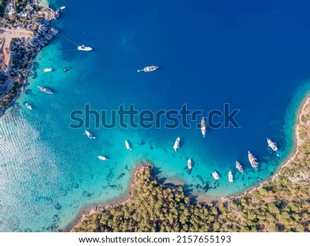 Aerial drone footage of daily tour boats and private yachts anchored in Cennet Bay, located in Selimiye village of Marmaris District of Muğla City, Turkey.