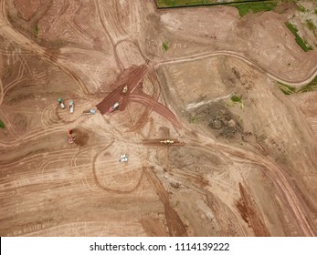 Aerial Drone Image (top View) Of A Construction Site.  Heavy Equipment Is Grading The Land, Moving And Flattening Out Red Clay Soil.