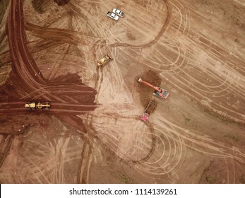 Aerial drone image (top view) of a construction site.  Heavy equipment is grading the land, moving and flattening out red clay soil.