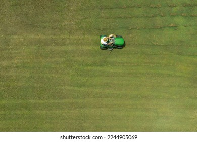 Aerial drone landscape view of Australian man riding ride on lawn mower cutting green grass. Real people. Copy space - Shutterstock ID 2244905069