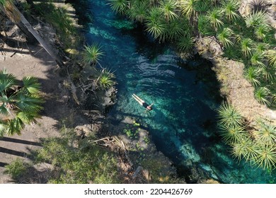 Aerial drone landscape view of young Australian tourist woman swimming in Bitter Springs natural thermal hot pools in the Northern Territory of Australia. - Shutterstock ID 2204426769
