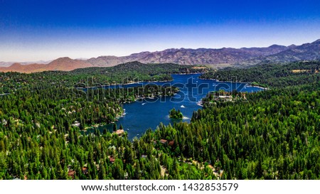 Aerial, drone panorama of Lake Arrowhead in the San Bernardino Mountains, California on a clear, summer day with blue water and sky, purple mountains and green trees