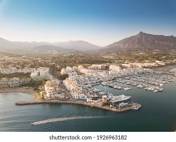 Aerial drone perspective of beautiful sunset over luxury Puerto Banus Bay in Marbella, Costa del Sol. Expensive lifestyle, luxury yachts. La concha mountain in background. Nueva Andalucía area