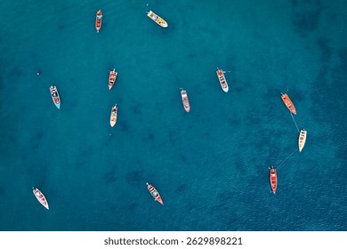 Aerial drone perspective capturing multiple vibrant fishing boats scattered across stunning turquoise Caribbean waters in St. Lucia. The wooden vessels create a striking pattern against the blue sea