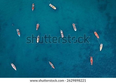 Aerial drone perspective capturing multiple vibrant fishing boats scattered across stunning turquoise Caribbean waters in St. Lucia. The wooden vessels create a striking pattern against the blue sea