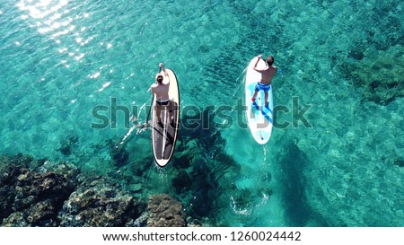 Aerial drone photo of 2 fit men practising SUP or Stand Up Paddle surf board in mediterranean turquoise open sea