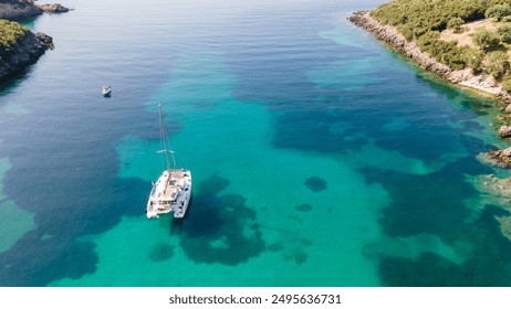 Aerial drone photo of beautiful catamaran sailing yacht anchored in tropical exotic turquoise sea exotic bay. Drone view - birds eye angle. Yachting and travel concept. Beautiful sailing catamaran