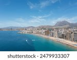Aerial drone photo of the beautiful city of Benidorm in Spain in the summer time showing the Playa de Levante beach and high rise apartments and hotels on the beach front on a sunny summers day