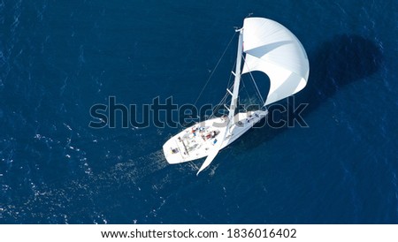 Aerial drone photo of beautiful sailboat with white sails cruising deep blue sea in low speed near Mediterranean destination port