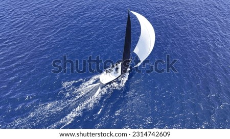 Aerial drone photo of beautiful sailing boat with white sails cruising deep blue Aegean sea, Greece