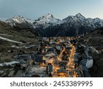 Aerial drone photo Blue Hour French alps in winter, Rhone Alpes in France Europe. Les deux alpes village in spring time. Town in the alps mountains during sunset. Winter French Alpes town from drone