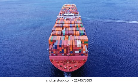 Aerial Drone Photo Of Bow From Huge Fully Loaded Container Tanker Ship Carrying Truck Size Colourful Containers In Deep Blue Open Ocean Sea