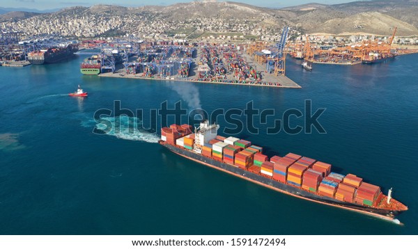 Aerial drone photo of container cargo carrier\
leaving industrial port of Perama for Mediterranean destination,\
Attica, Greece
