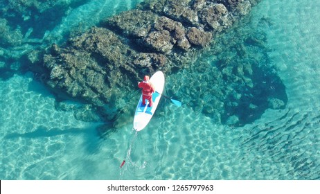 Aerial drone photo of fit man dressed as Santa Claus practising SUP or Stand Up Paddle in tropical turquoise sea - Powered by Shutterstock