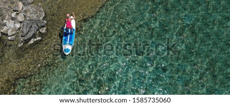 Aerial drone photo of fit unidentified woman practising in SUP board or Stand UP Paddle surf board in tropical exotic island turquoise sea