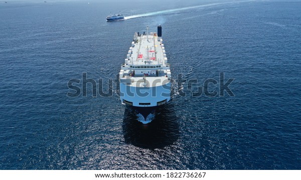 Aerial\
drone photo of huge car carrier ship RO-RO (Roll on Roll off)\
cruising in Mediterranean deep blue Aegean\
sea