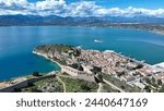 Aerial drone photo of iconic Acronafplia fortress overlooking old city of Nafplio below famous castle of Palamidi as seen in a spring morning with beautiful clouds and deep blue sky, Argolida, Greece