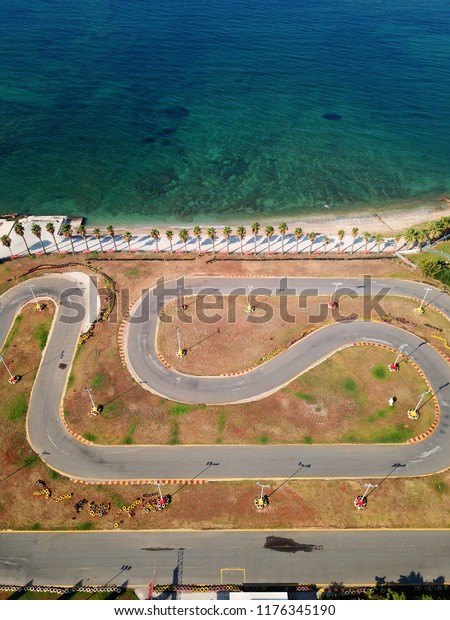 Aerial drone photo of kart track next to\
the ocean with sandy beach and coconut\
trees