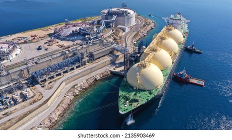 Aerial drone photo of LNG (Liquified Natural Gas) tanker anchored in small LNG industrial islet of Revithoussa equipped with tanks for storage, Salamina, Greece - Shutterstock ID 2135903469