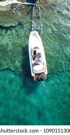 Aerial Drone Photo Of Luxury Speed Boat Being Taken Out Of Water By Trailer In Tropical Rocky Beach With Crystal Clear Waters