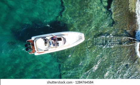 Aerial drone photo of luxury speed boat being taken out of water by trailer in tropical rocky marina
