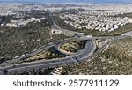 Aerial drone photo of modern Attiki Odos toll multilevel interchange highway with Kaisariani and mount Hymetus, Athens, Attica, Greece