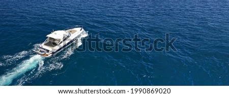Aerial drone photo of small luxury yacht cruising in deep blue waters of Mykonos island, Cyclades, Greece