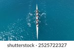 Aerial drone photo of sport canoe operated by team of young trained athletes in deep emerald sea