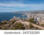 Aerial drone photo of the town of Benidorm in Spain showing the whole of the town in the summer time showing the famous cross known as The La Creu de Benidorm