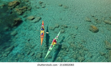 Aerial drone photo of women team of sport kayak paddling in iconic beach and small cove of Tsigrado, Milos island, Cyclades, Greece - Powered by Shutterstock