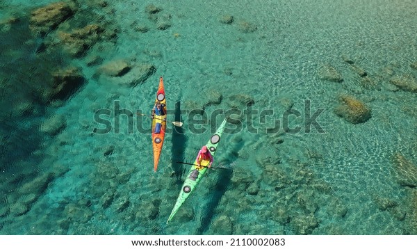 Aerial drone photo of women team of sport kayak\
paddling in iconic beach and small cove of Tsigrado, Milos island,\
Cyclades, Greece