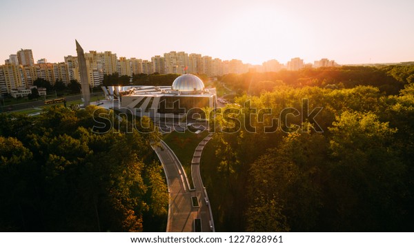 Aerial drone\
shoot with top view of Victory Park and Belarusian Great Patriotic\
War Museum in Minsk, Belarus. Beauty sunset with architecture and\
trees, clean blue sky.