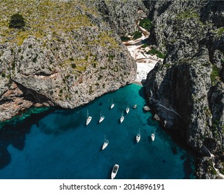 Aerial drone Shot above the remote beach at Torrent de Pareis where towering cliffs surround a stony beach and multiple boats anchored up - Shutterstock ID 2014896191
