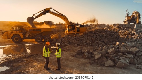 Aerial Drone Shot Of Construction Site On Sunny Evening: Caucasian Male Civil Engineer Talking To Hispanic Female Urban Planner and Using Tablet. Industrial Excavator Loading Rocks Into A Truck. - Powered by Shutterstock