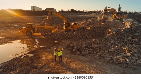 Aerial Drone Shot Of Construction Site On Sunny Evening: Industrial Excavators Digging Rocks And Loading Them Into A Truck. Engineer And Architect Observing Process, Discussing Real Estate Project - Powered by Shutterstock