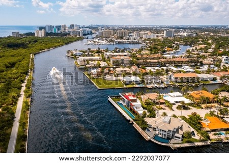 Aerial drone shot of the Coral Ridge neighborhood, in Fort Lauderdale, Miami, USA, commercial area, with canals and boats sailing, luxury houses and mansions, abundant tropical vegetation around, blue