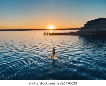 Aerial drone shot of girl at stand up paddle boards SUP in silhouette near pier at lake Kapchagay in Kazakhstan at sunset. - Powered by Shutterstock