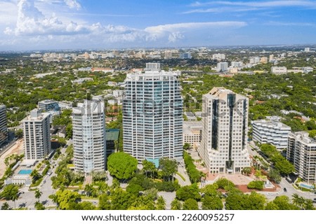 Aerial drone shot of Grovenor House Coconut Grove in Miami, abundant tropical vegetation around, modern buildings and towers, blue sky with clouds and city in the background
