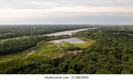 An aerial drone shot high above a green and grassy marshlands on a sunny day on Long Island, NY.