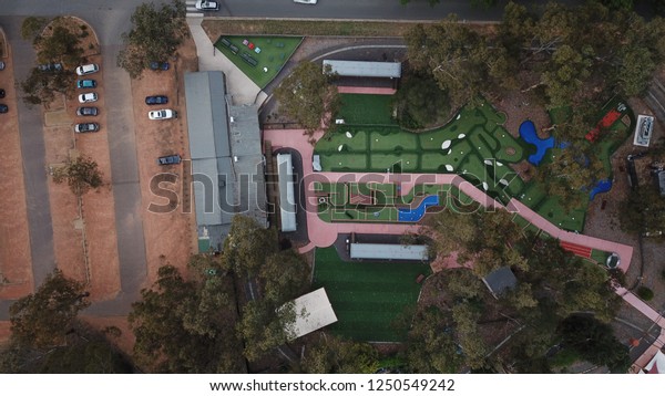 Aerial drone shot over mini gold course and gravel\
car park