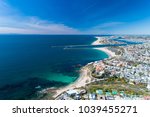 Aerial drone shot over Newport Beach in Orange County, California with coastal homes, blue skies, beaches and harbor entrance in view.