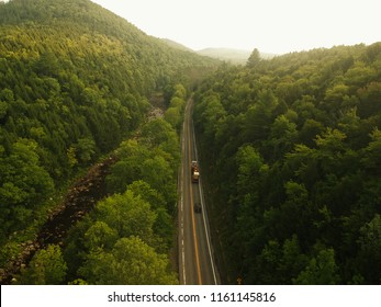 Aerial Drone Shot Of A Truck And A Car Driving On A Road In The Misty Adirondack Mountains